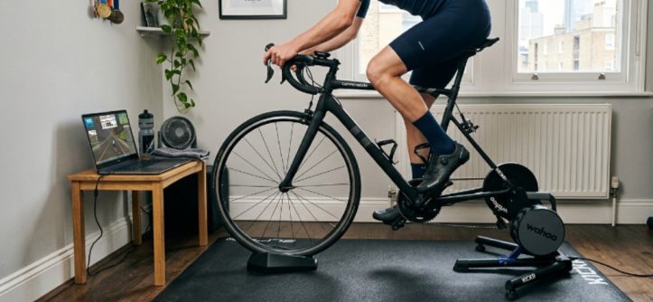 High-density bike trainer mat placed under a direct-drive turbo trainer in a small apartment workout space