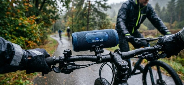 A waterproof Bluetooth speaker mounted on a bicycle handlebar during a rainy outdoor ride